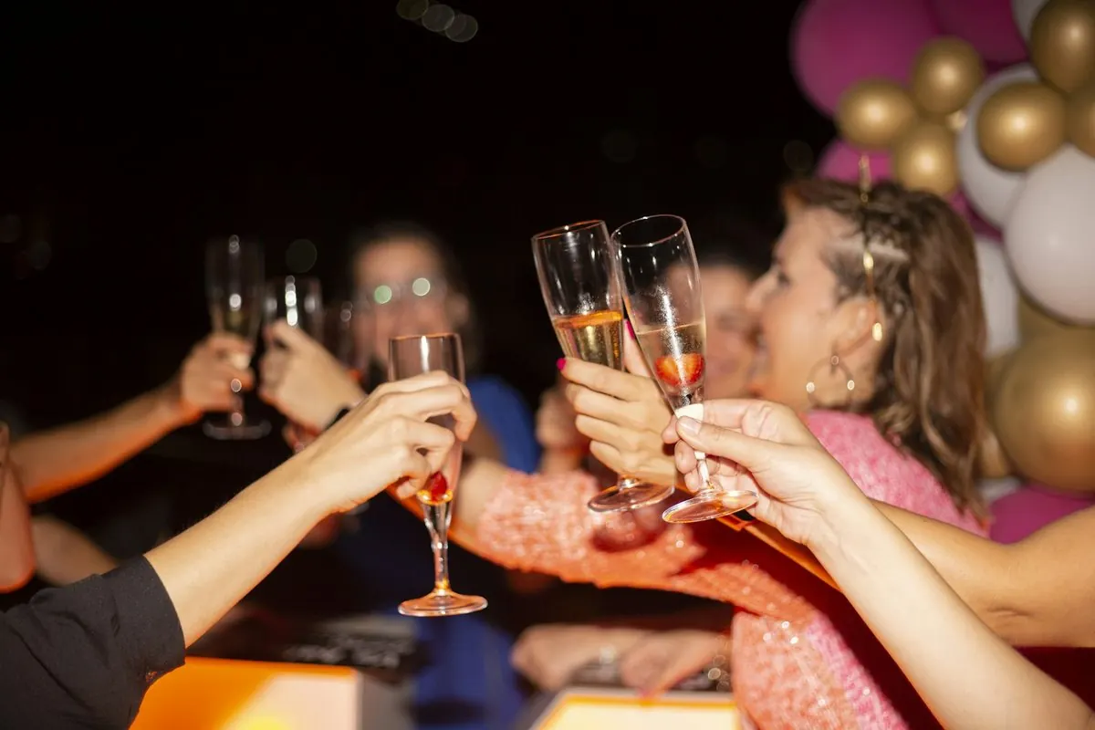 Friends clink champagne glasses in front of balloons