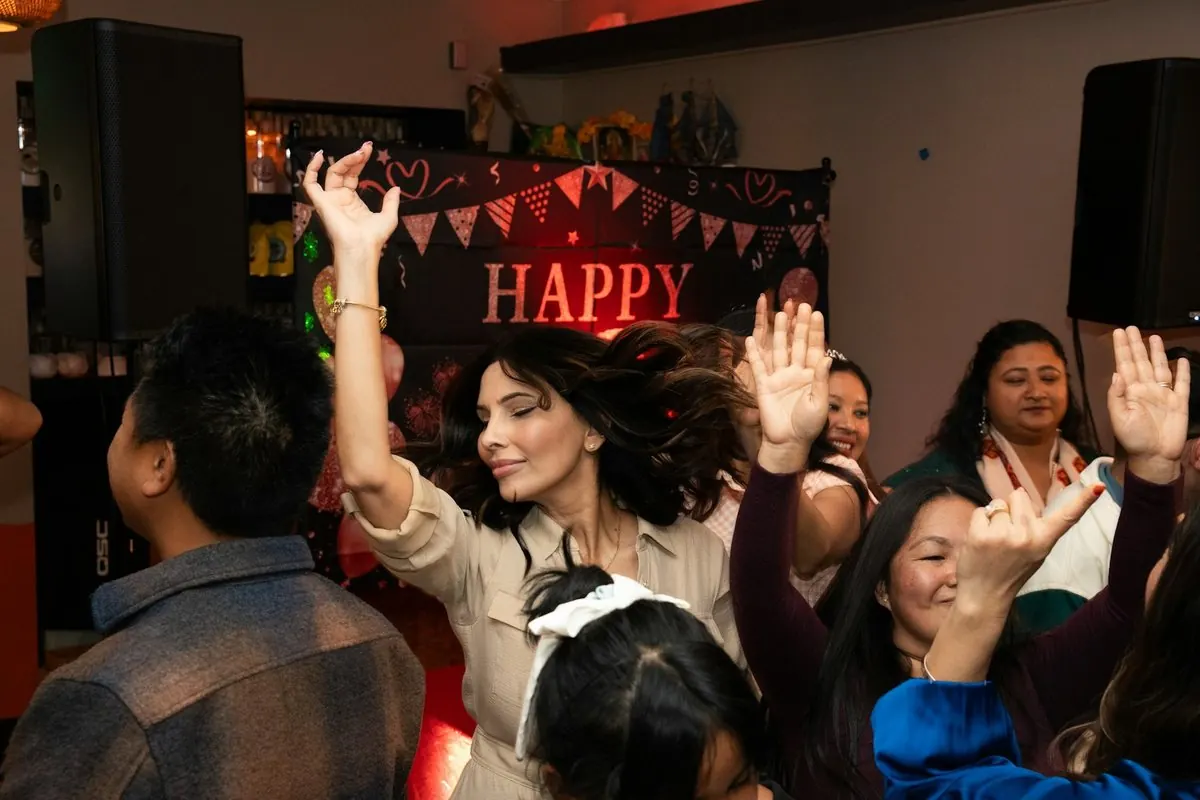 Guests dance with their arms up under a Happy garland