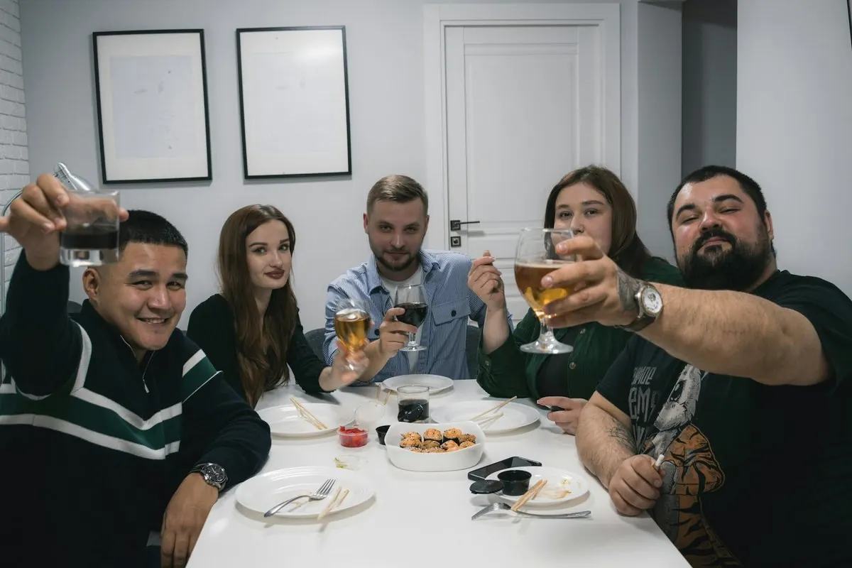 Friends raise their glasses around a table in an apartment