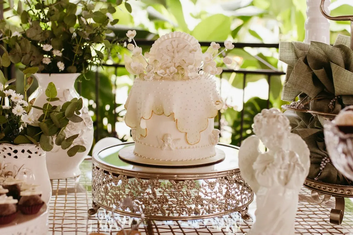 Un gâteau blanc décoré, entouré de statuettes d'anges