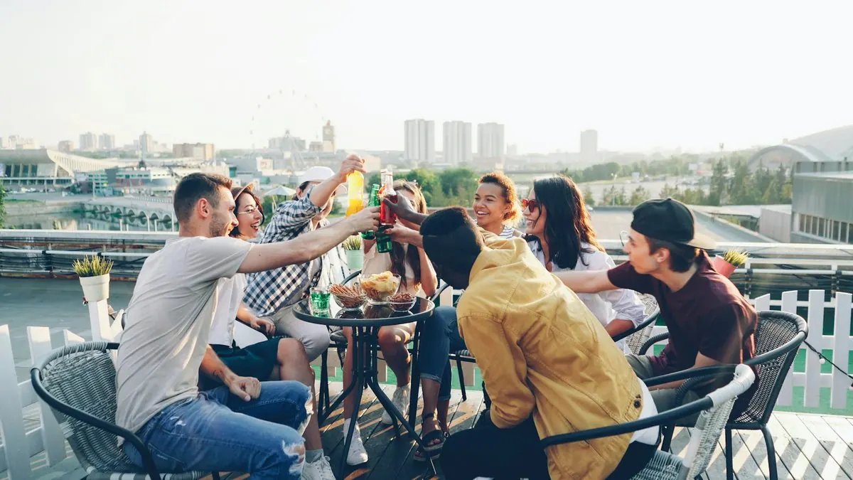 Une bande d'amis trinque sur un toit au coucher du soleil