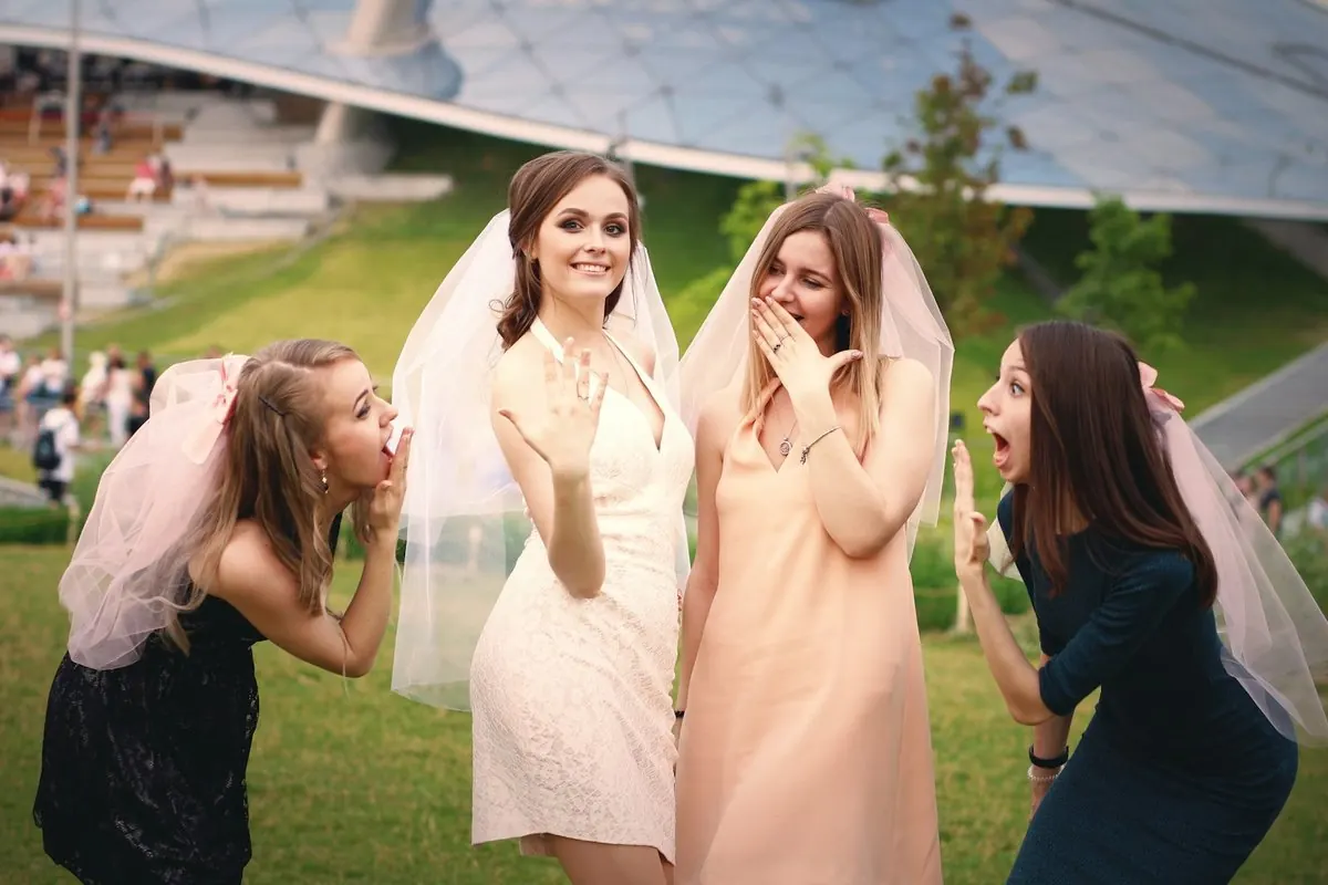Des amies en voiles de mariée éclatent de rire dans un jardin