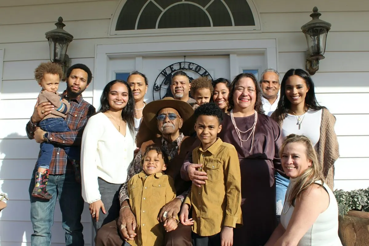 Une grande famille pose devant une maison