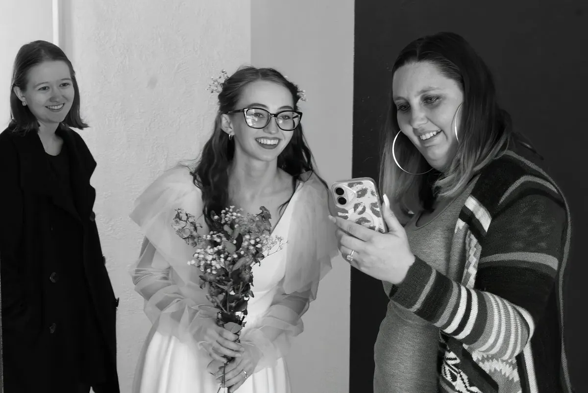 La mariée et une invitée rient devant les photos sur un téléphone